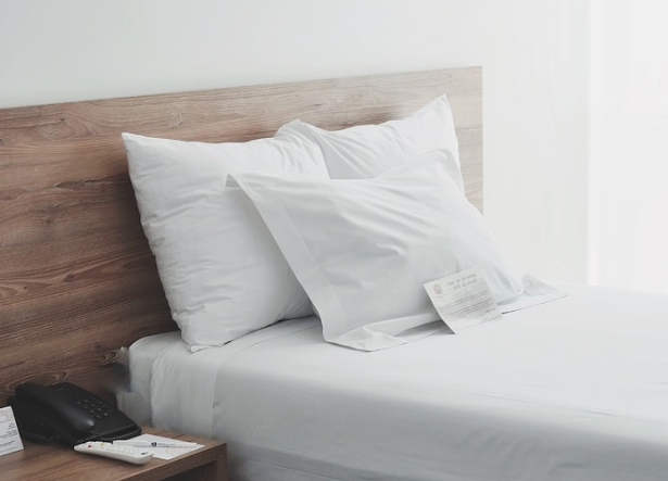 a bed in a hotel room with white bedsheet